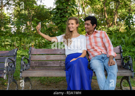 Happy multi ethnic couple smiling while taking selfie picture wi Stock Photo