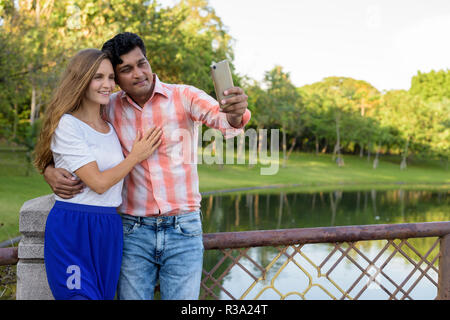 Happy multi ethnic couple smiling and in love while taking selfi Stock Photo