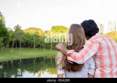 Back view of multi ethnic couple in love while looking at peacef Stock Photo