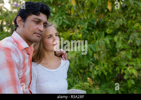 Multi ethnic couple thinking and in love at peaceful green park  Stock Photo