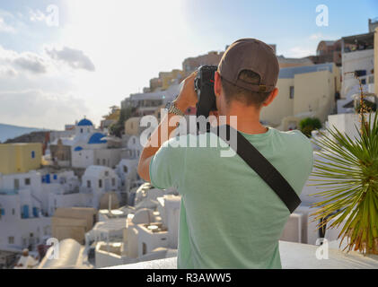 A traveler standing and taking pictures of Oia Town in Santorini, Greece. Stock Photo