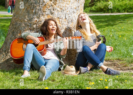two girlfriends making music in the park Stock Photo