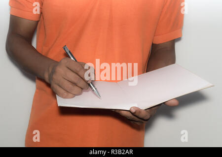 Selective focus on hand writing with pen, notebook. African American Asian business man standing and working with documents in office, analyzing proje Stock Photo