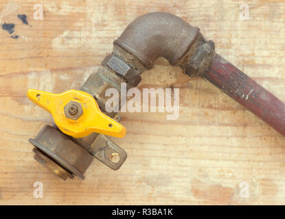 Old gas with yellow ball valve on wooden background Stock Photo