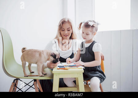 mother and child daughter draws are engaged in creativity in kindergarten. small pug with them Stock Photo