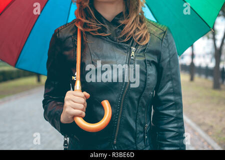 girl in a black leather jacket with a multi-colored umbrella in her hands on the mall Stock Photo
