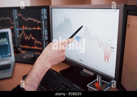 Analyzing data. Close-up of young businessman pointing on the data presented in the chart with pen while working in creative office Stock Photo