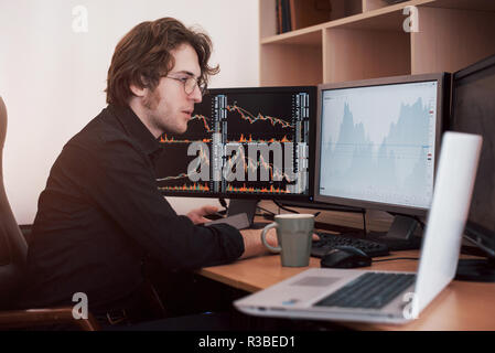 Businessmen trading stocks online. Stock broker looking at graphs, indexes and numbers on multiple computer screens. Business success concept Stock Photo