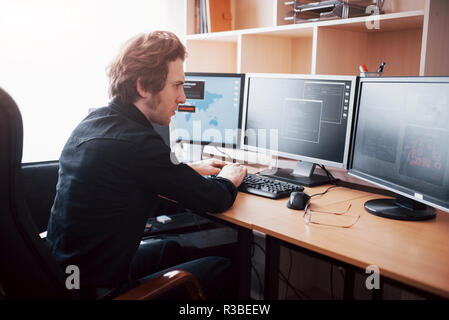 Male programmer working on desktop computer with many monitors at office in software develop company. Website design programming and coding technologies Stock Photo