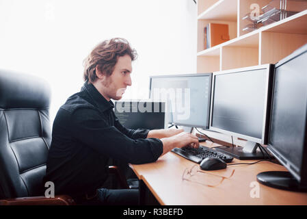 Male programmer working on desktop computer with many monitors at office in software develop company. Website design programming and coding technologies Stock Photo