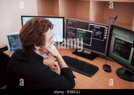 Male programmer working on desktop computer with many monitors at office in software develop company. Website design programming and coding technologies Stock Photo