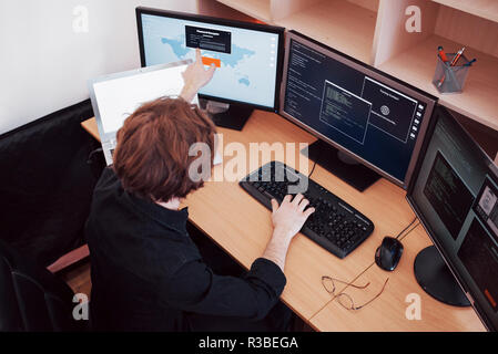 Male programmer working on desktop computer with many monitors at office in software develop company. Website design programming and coding technologies Stock Photo