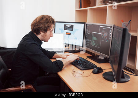 Male programmer working on desktop computer with many monitors at office in software develop company. Website design programming and coding technologies Stock Photo
