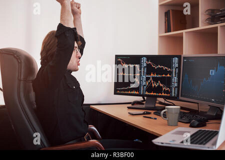 Young stock trader broker stretching hands at workplace, he first achieved great success on the stock market Stock Photo