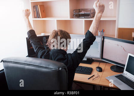Young stock trader broker stretching hands at workplace, he first achieved great success on the stock market Stock Photo