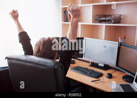 Young stock trader broker stretching hands at workplace, he first achieved great success on the stock market Stock Photo