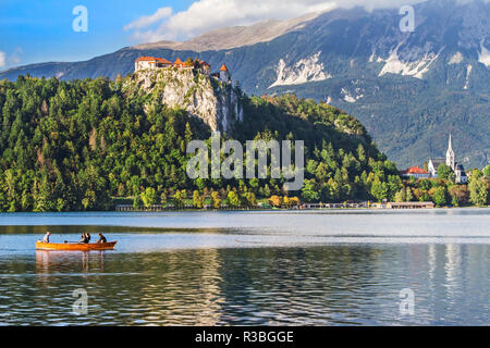 Traditional wooden pletnja rowing boat to ferry tourists to St. Mary's Church of Assumption on the island beyond, Lake Bled, Slovenia Stock Photo