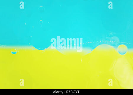 A beautiful and colorful macro of oil bubbles on water with two color as high contrast background, blue and yellow Stock Photo