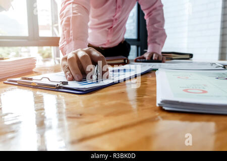 Businessman pointing monthly graph chart. Data analyzing to find out the result. Stock Photo