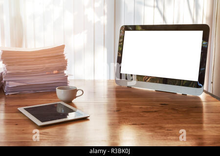 A cup of coffee with tablet and office supplies on office desk. Wooden table with office supplies in home office at morning Stock Photo