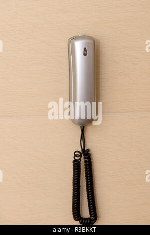 A landline phone hanging on the wall Stock Photo