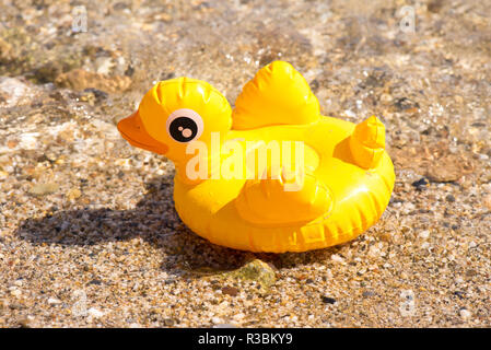 Yellow inflatable duck on the beach near the sea Stock Photo