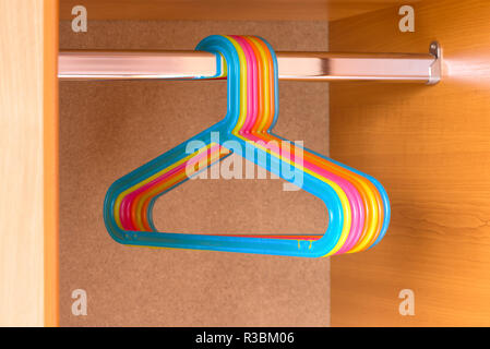 Colorful empty hangers in a wood wardrobe Stock Photo