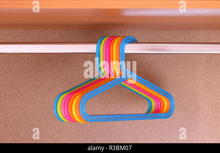 Colorful empty hangers in a wood wardrobe Stock Photo