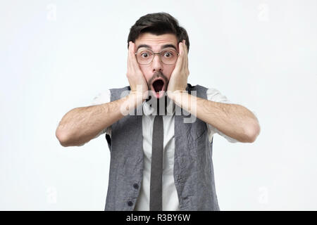 Emotional scared brunet male looks with frightened expression as sees something awful in front Stock Photo