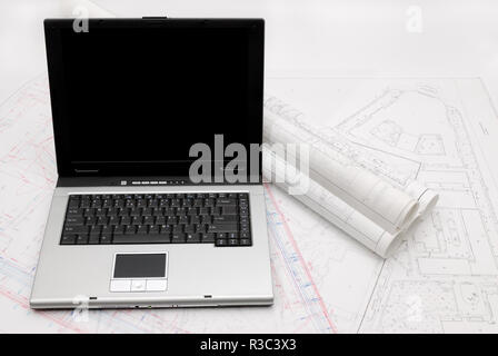 Computer with architectural plans lying on table Stock Photo