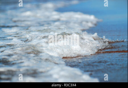 Beach, edge of sea water with white seafoam Stock Photo