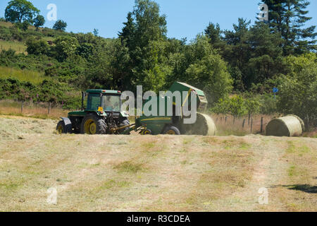 Tractor making hay bales at The Bog, Stiperstones, Shropshire, UK Stock Photo