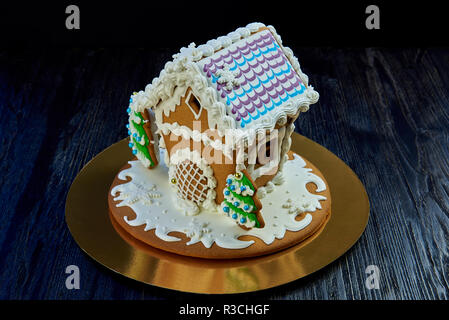 Christmas gingerbread house on a dark wooden surface against a black background. Stock Photo