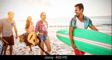 Friends carrying a surfboard and basket Stock Photo