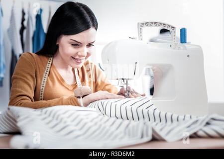 Designers studio. Happy skilled tailor using professional equipment while creating clothes Stock Photo