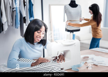 Small business. Positive young women doing dresses while being at work Stock Photo