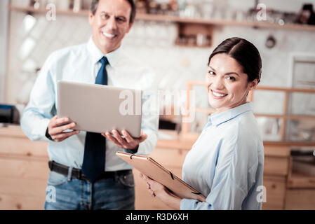 Personal assistant. Nice smart woman looking at you while working as a personal assistant of a businessman Stock Photo