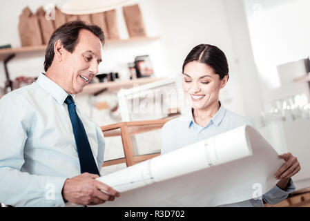 Optimization plan. Nice positive people discussing their business while looking at the drawing Stock Photo