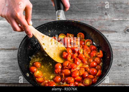 Person cooking dinner for italian cuisine, basic tomato sauce for pasta, healthy food making, detailed view of hands and pan Stock Photo