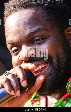 Faversham Hop Festival 2018. Close up of face, Afro-Caribbean man, Adrian Benn from the group Groove Zoo singing into hand held microphone. Daytime. Stock Photo