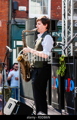 Faversham Hop Festival 2018, Invicta Jazz Orchestra on stage. Lone saxophone player standing on edge of stage performing solo musical number. Stock Photo