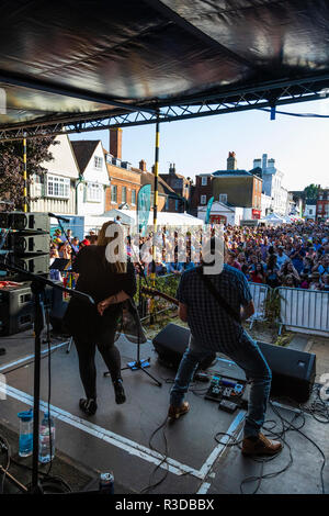 Faversham Hop Festival. Back of stage viewpoint, rock band, Creek, performing before large outdoor audience, most with arms raised. Daytime. Stock Photo