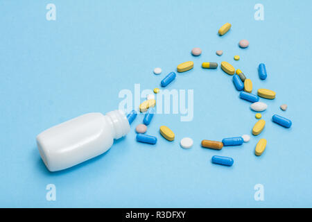 White bottle with different pills and capsules in the form of a heart on blue background Stock Photo