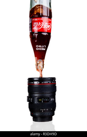 Puring coca-cola from the bottle to a 'lens' mug Stock Photo