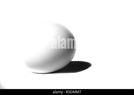 A single white egg on a white background casting a shadow Stock Photo