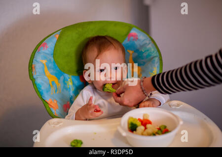 feeding baby - adorable baby boy eating broccoli Stock Photo