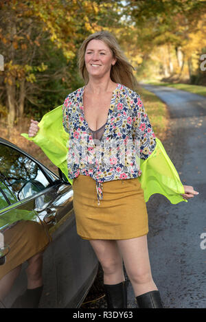 Female motorist putting on a reflective safety jacket on the roadside Stock Photo