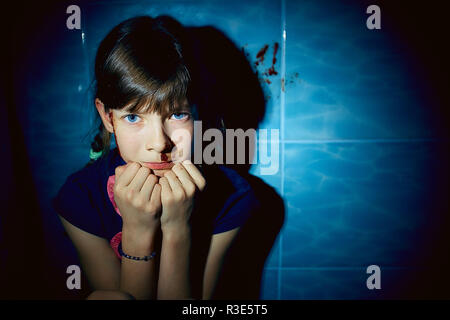 teen girl with blood on her face hiding in bathroom, domestic violence Stock Photo