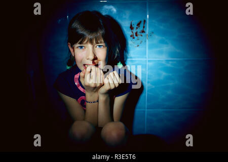 teen girl with blood on her face hiding in bathroom, domestic violence Stock Photo