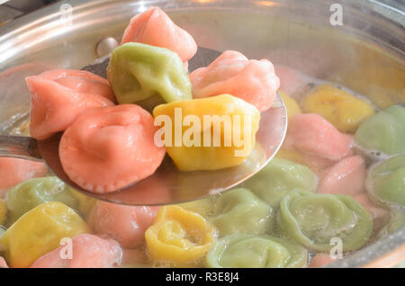 Multicolored ravioli for a festive menu are cooked in a pan and on a ...